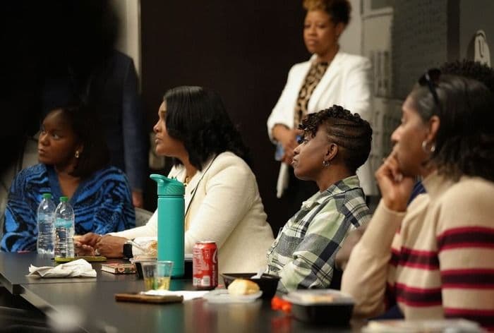 Diverse group of women sitting at a table, attentively listening in a meeting.