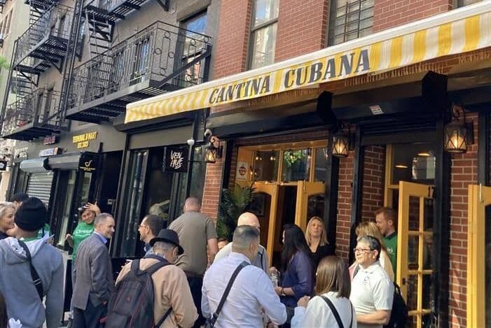 Cantina Cubana restaurant exterior with a yellow and white striped awning, people gathered outside.