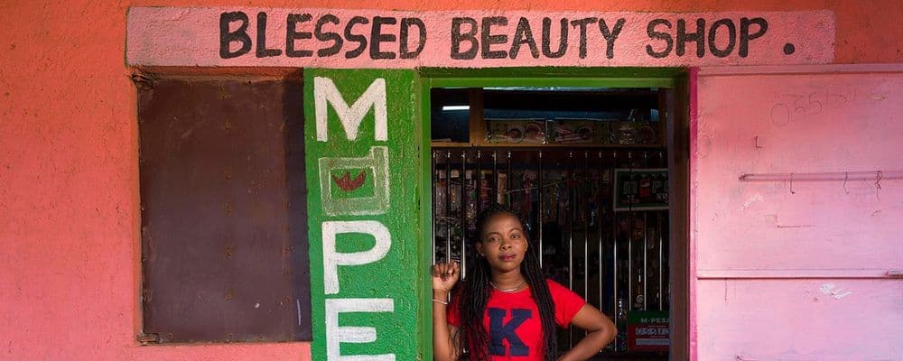 A young woman stands in front of the Blessed Beauty Shop.