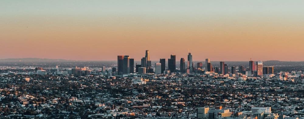 City skyline with tall buildings against a warm, gradient sky during dusk or dawn.