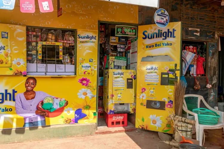 A vibrant yellow shop front promoting Sunlight products with a smiling woman graphic.