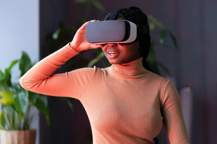 A Black woman looks surprised while wearing a virtual reality headset indoors.