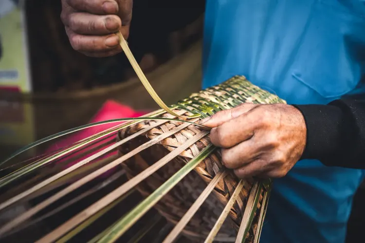 Close-up of hands skillfully weaving natural fibers into a traditional basket or hat.