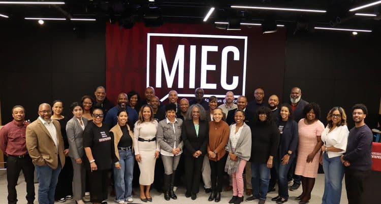 Diverse group of adults stands in front of Fallar Hall for a group photo.