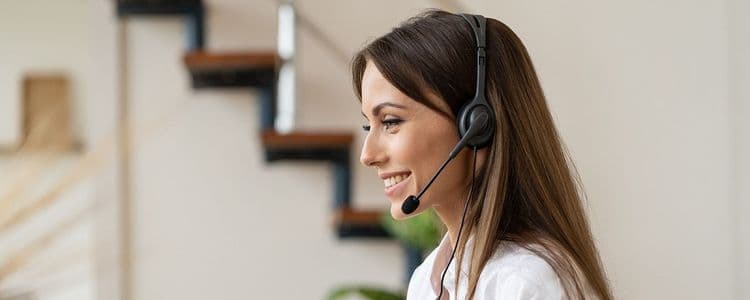 Young smiling woman wearing a black headset with a microphone, looking forward intently.