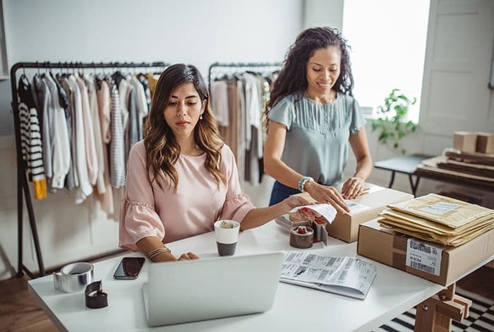 Two women manage online orders and package products in their small business.
